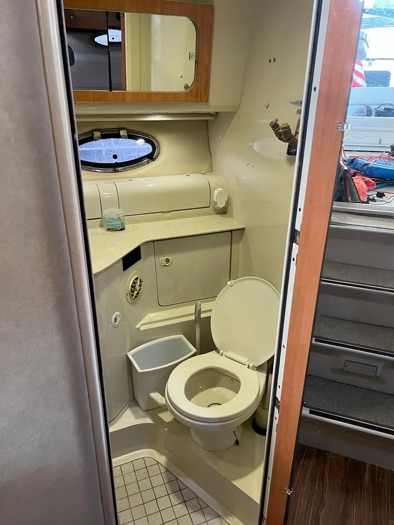 Slide: The Image of 1999 Regal 402 boat bathroom with toilet, sink, mirror, and porthole window. - 37