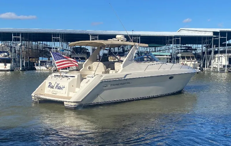 Slide: The Image of 1999 Regal 402 boat docked, displaying an American flag, under clear blue skies. - 4