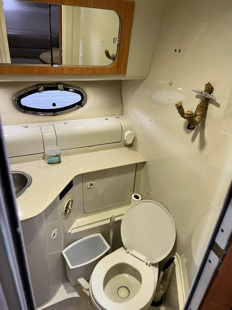 Slide: The Image of 1999 Regal 402 boat bathroom with toilet, sink, mirror, and porthole window. - 42