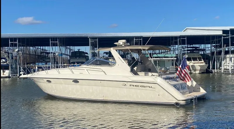 Slide: The Image of 1999 Regal 402 yacht docked in marina, American flag displayed, clear blue sky. - 5