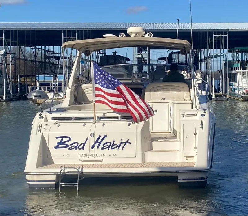 Slide: The Image of 1999 Regal 402 boat named "Bad Habit" with American flag, docked in marina. - 8