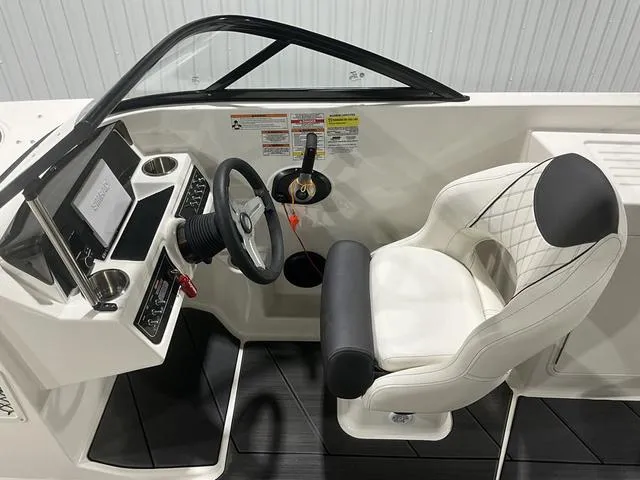 Slide: The Image of 2023 Bayliner DX2250 boat cockpit with steering wheel and white captain's chair. - 12
