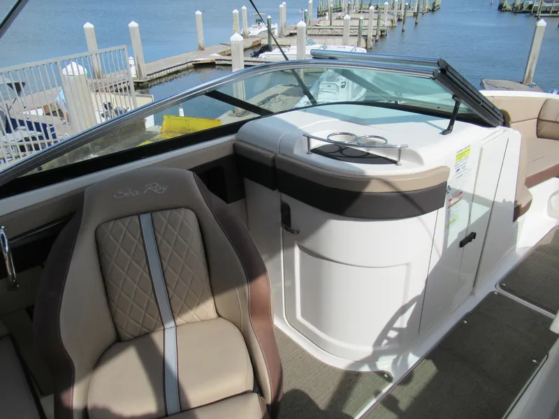 Slide: The Image of 2016 Sea Ray SunDeck 220 interior with beige seating and waterfront view. - 11