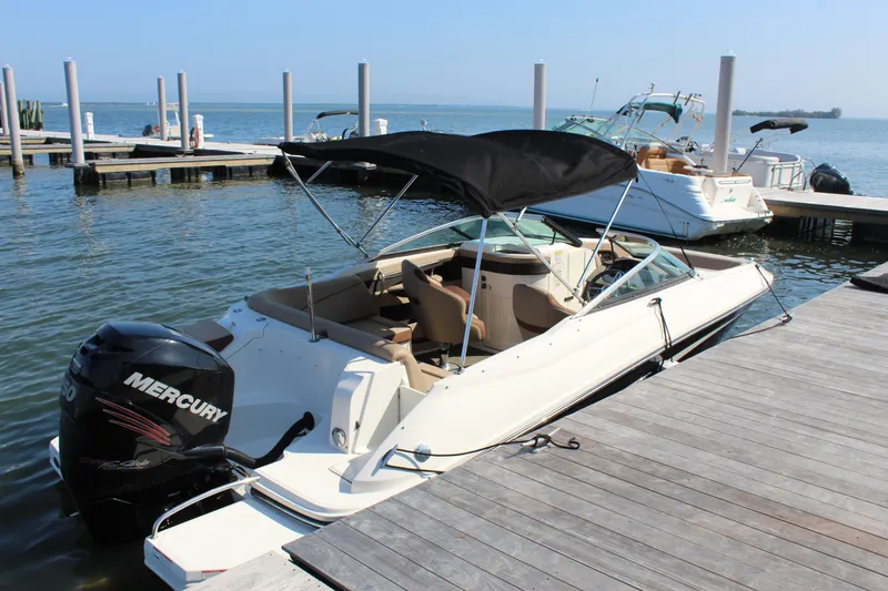 Slide: The Image of 2016 Sea Ray SunDeck 220 boat docked with Mercury outboard motor and black canopy. - 19