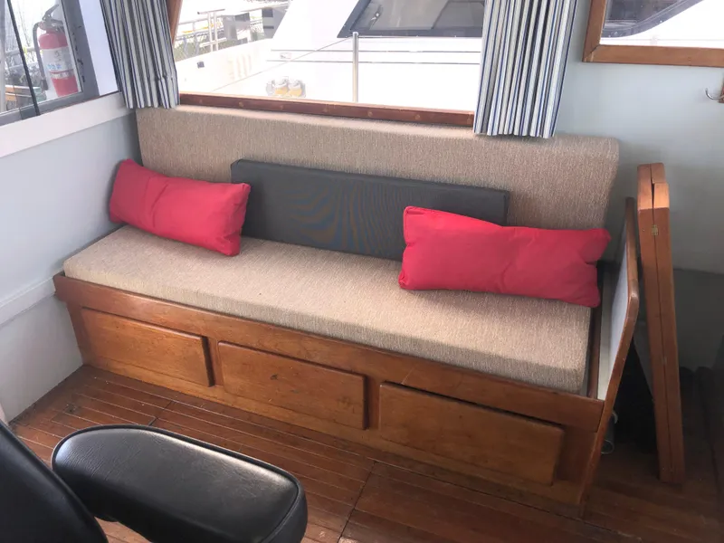 Slide: The Image of Cozy seating area on 1981 Rough Water 37 Sedan with red cushions and wooden storage. - 19