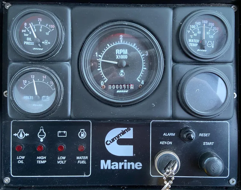 Slide: The Image of 1981 Rough Water 37 Sedan marine control panel with gauges and Cummins branding. - 23