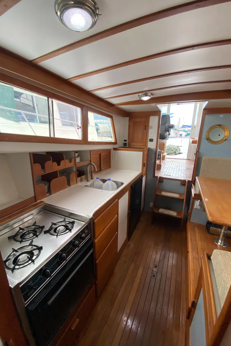 Slide: The Image of 1981 Rough Water 37 Sedan boat interior with wooden flooring and compact kitchen. - 31