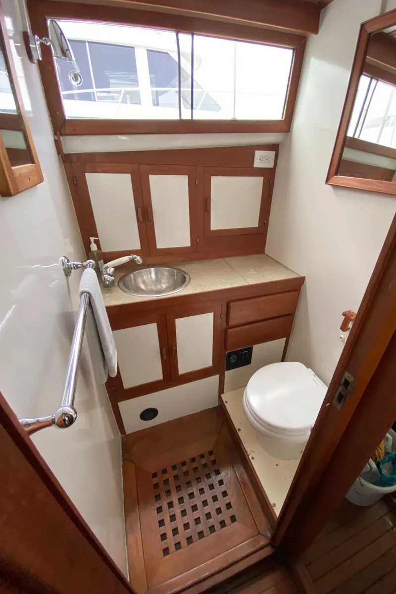 Slide: The Image of 1981 Rough Water 37 Sedan boat bathroom with wooden cabinetry and stainless steel sink. - 38