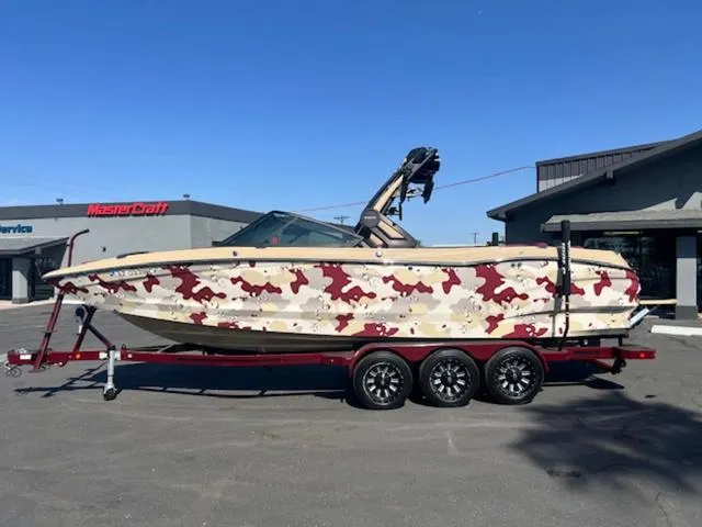 Slide: The Image of 2022 MasterCraft X26 boat with camouflage design on a trailer in a parking lot. - 1