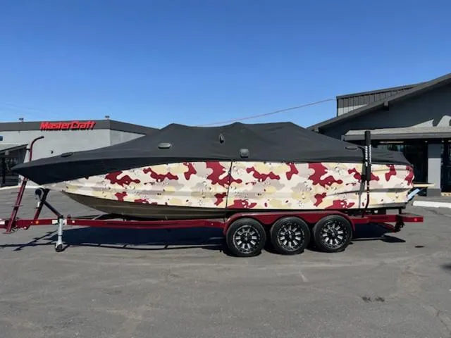 Slide: The Image of 2022 MasterCraft X26 boat with camouflage cover on a trailer. - 23