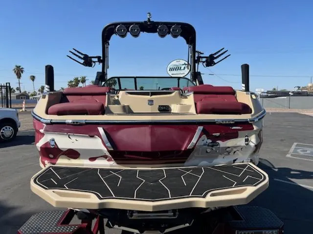 Slide: The Image of 2022 MasterCraft X26 boat with maroon and beige design, parked outdoors. - 7