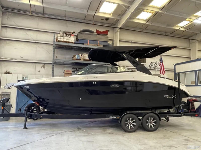 Slide: The Image of 2024 Sea Ray SLX 260 Surf boat in a warehouse, on a trailer. - 2