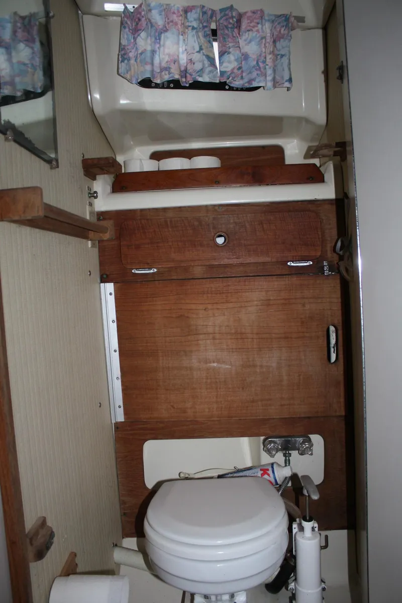 Slide: The Image of 1979 Pearson 323 sailboat bathroom with wooden cabinetry and compact toilet. - 19