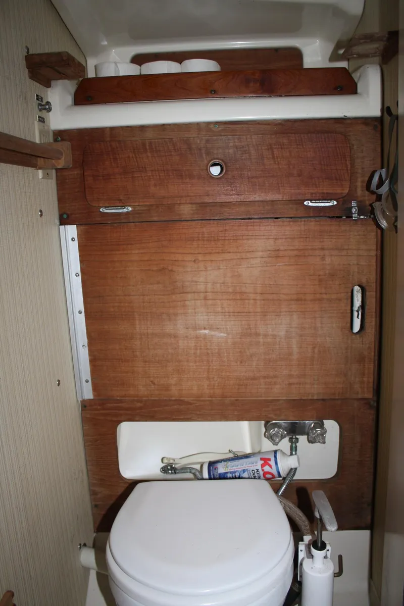 Slide: The Image of 1979 Pearson 323 sailboat bathroom with wooden cabinetry and compact toilet. - 20