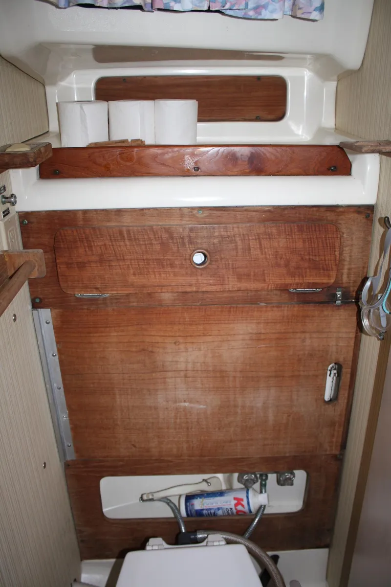 Slide: The Image of 1979 Pearson 323 yacht interior with wooden cabinetry and storage shelves. - 21