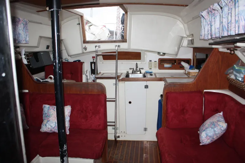 Slide: The Image of Interior of a 1979 Pearson 323 sailboat with red seating and a compact kitchen area. - 24