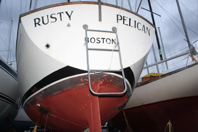 Slide: The Image of 1979 Pearson 323 sailboat named "Rusty Pelican" in Boston, featuring a red hull. - 7