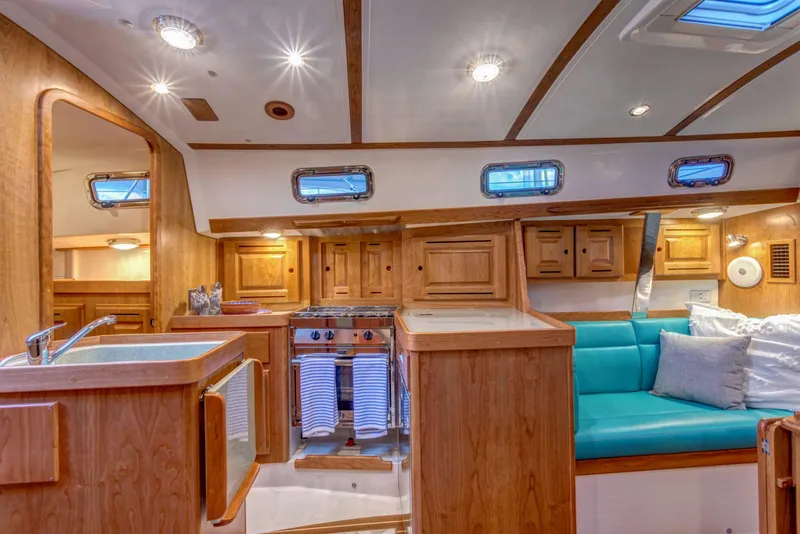 Slide: The Image of Interior of 2025 Tartan 365 sailboat with wooden cabinetry and turquoise seating. - 10