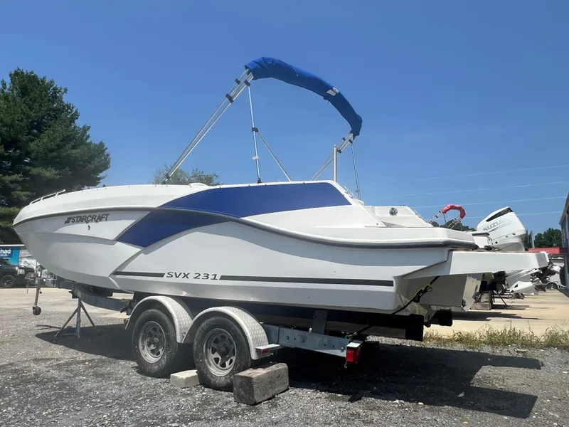 Slide: The Image of 2023 Starcraft SVX 231 OB DH boat on trailer, blue canopy, outdoor display. - 2