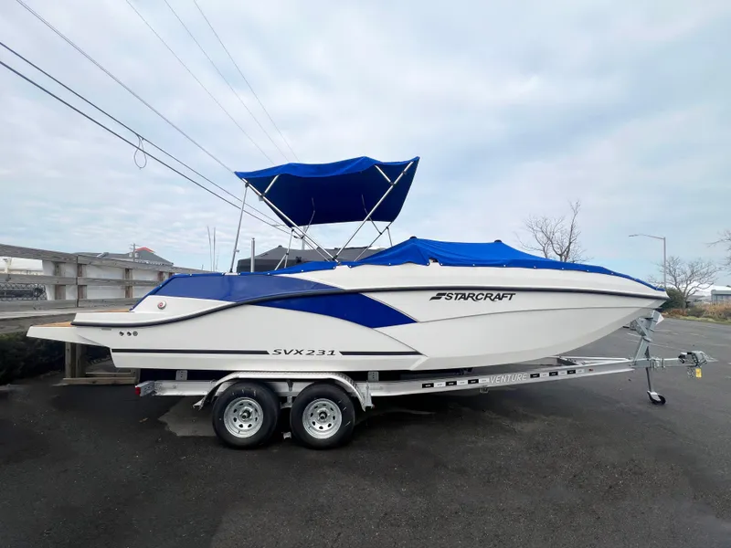 Slide: The Image of 2023 Starcraft SVX 231 OB DH boat on trailer with blue canopy. - 4