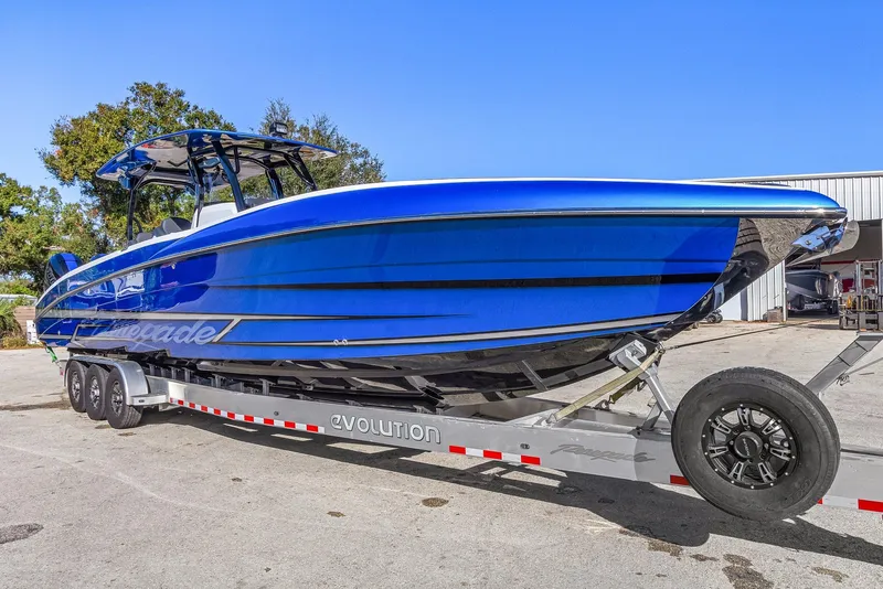 Slide: The Image of 2023 Renegade 38 Open boat on trailer, vibrant blue finish, parked outdoors. - 10