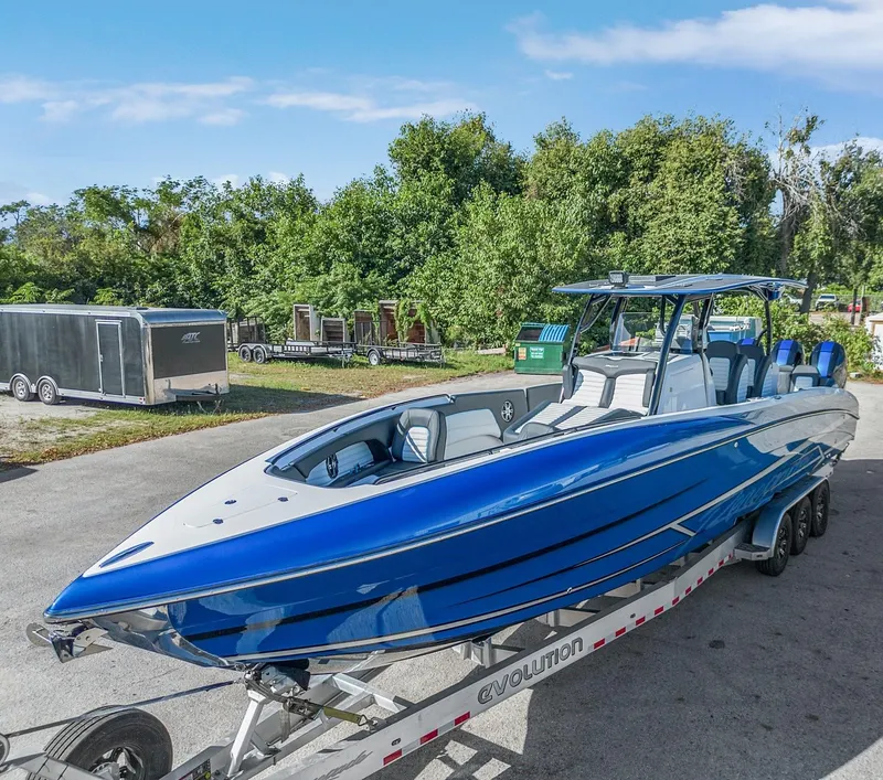 Slide: The Image of 2023 Renegade 38 Open boat on trailer, blue and white design, parked outdoors. - 43