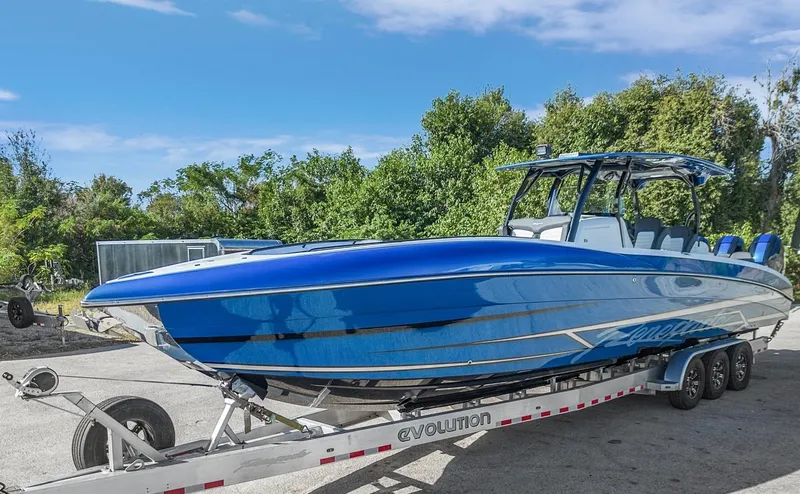 Slide: The Image of 2023 Renegade 38 Open boat on trailer, sleek blue design, parked outdoors. - 44