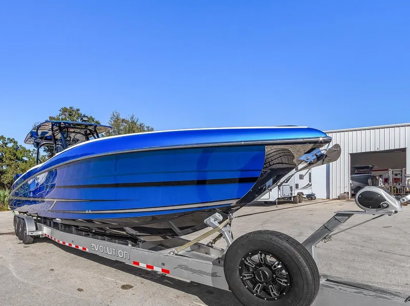 Slide: The Image of 2023 Renegade 38 Open boat on trailer, vibrant blue finish, parked outdoors. - 9