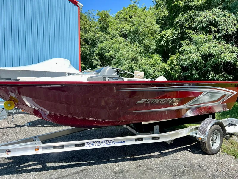 The Image of 2023 Starcraft Storm 166 SC boat on trailer, red exterior, parked outdoors. - 0