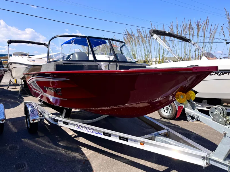 Slide: The Image of 2023 Starcraft Storm 166 DC boat on a trailer, red exterior, displayed outdoors. - 5