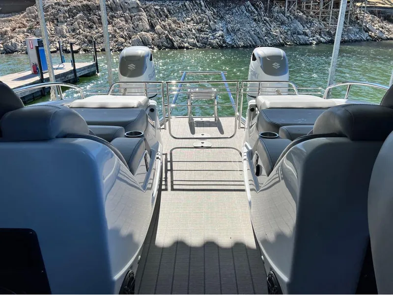 Slide: The Image of 2023 Manitou LX 25 SRW pontoon boat interior with dual engines and seating. - 18