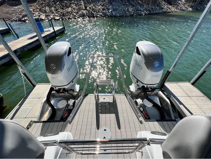 Slide: The Image of 2023 Manitou LX 25 SRW boat with dual Suzuki outboard motors on a sunny lake. - 19