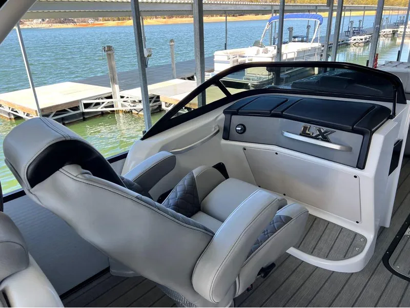 Slide: The Image of 2023 Manitou LX 25 SRW boat interior with split rear windshield, docked by a lake. - 21