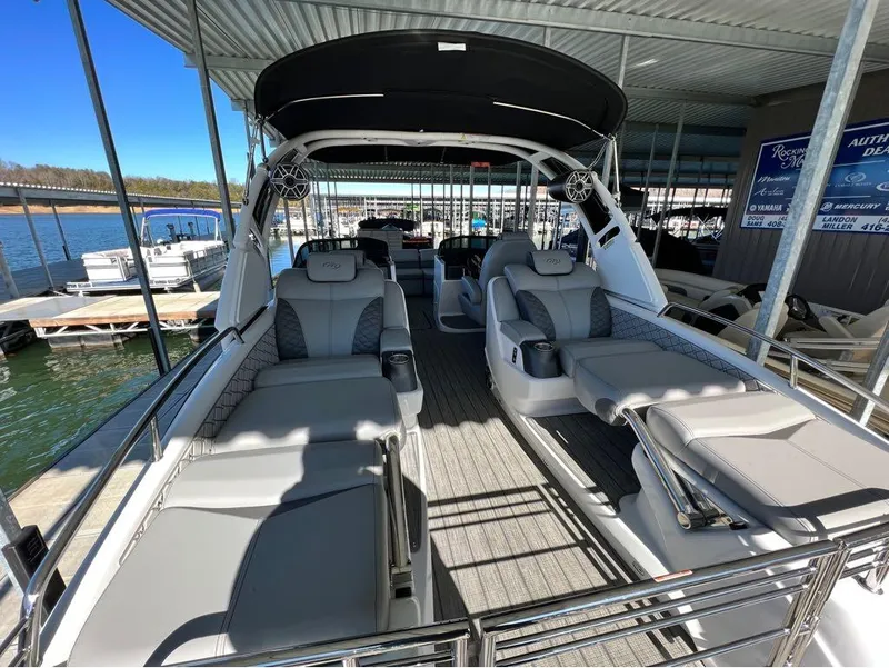 Slide: The Image of 2023 Manitou LX 25 SRW pontoon boat with luxurious seating at a marina. - 22