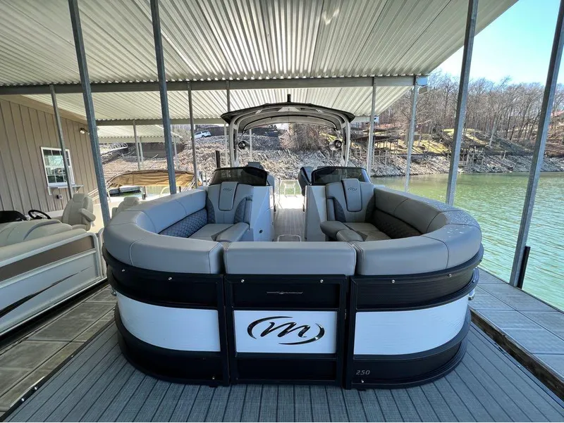 Slide: The Image of 2023 Manitou LX 25 SRW pontoon boat docked under a covered area. - 24
