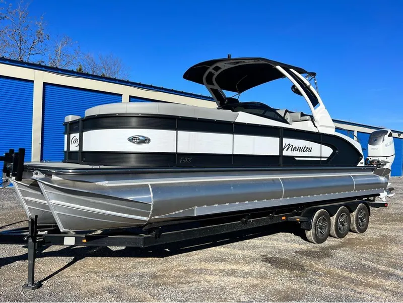 Slide: The Image of 2023 Manitou LX 25 SRW pontoon boat on trailer, parked outdoors. - 25