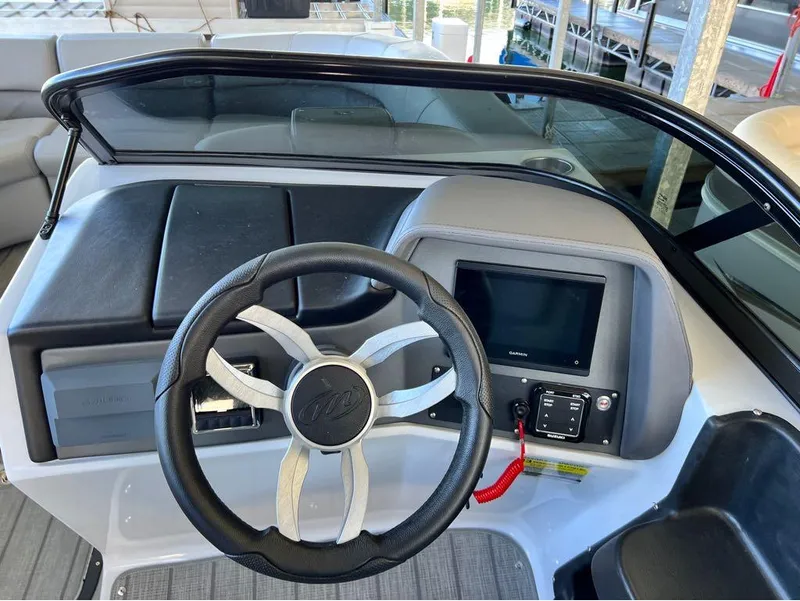 Slide: The Image of 2023 Manitou LX 25 SRW boat dashboard with steering wheel and Garmin display. - 29