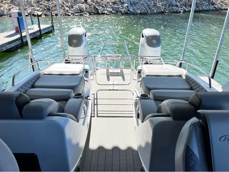 Slide: The Image of 2023 Manitou LX 25 SRW pontoon boat interior with plush seating and dual engines. - 30