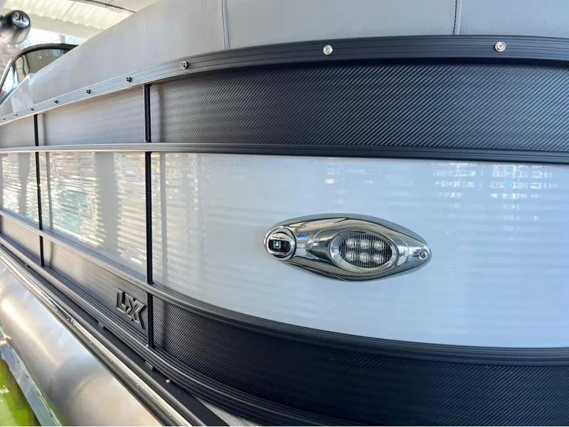 Slide: The Image of 2023 Manitou LX 25 SRW boat side view with sleek design and modern detailing. - 31