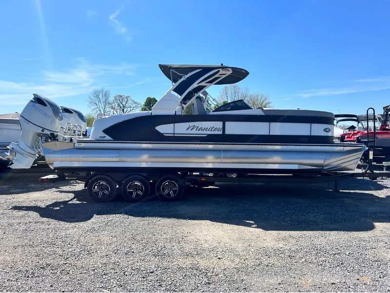 Slide: The Image of 2023 Manitou LX 25 SRW pontoon boat with dual engines on a trailer. - 32