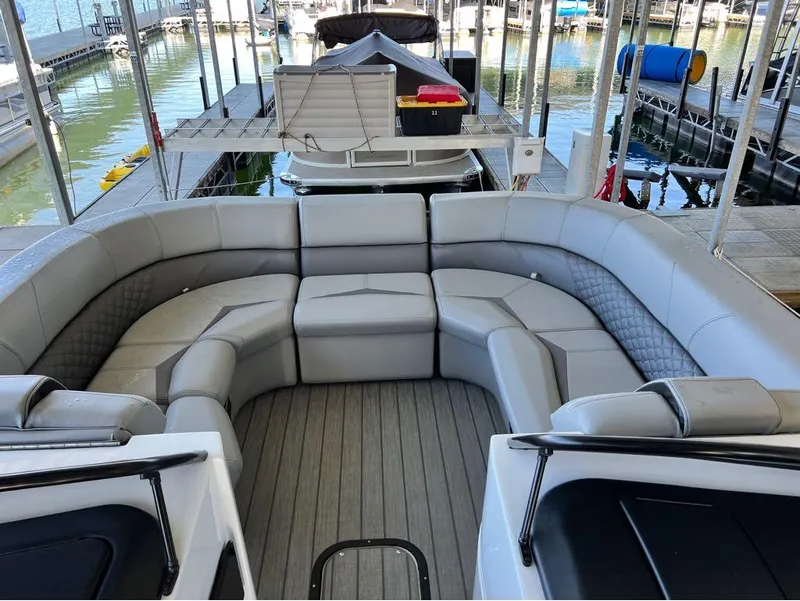 Slide: The Image of 2023 Manitou LX 25 SRW pontoon boat with spacious seating at a marina. - 35