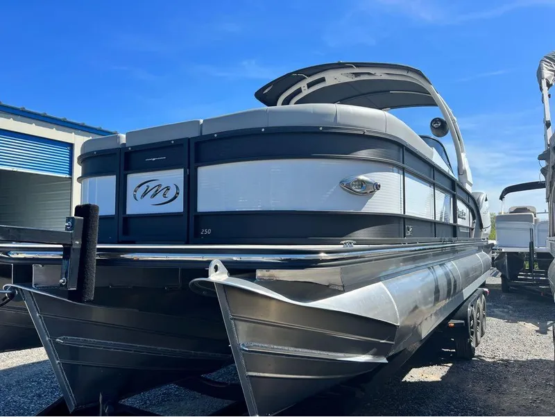 Slide: The Image of 2023 Manitou LX 25 SRW pontoon boat with split rear windshield, parked outdoors. - 4
