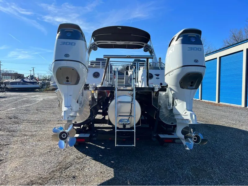 Slide: The Image of 2023 Manitou LX 25 SRW boat with dual 300 horsepower engines, parked outdoors. - 42