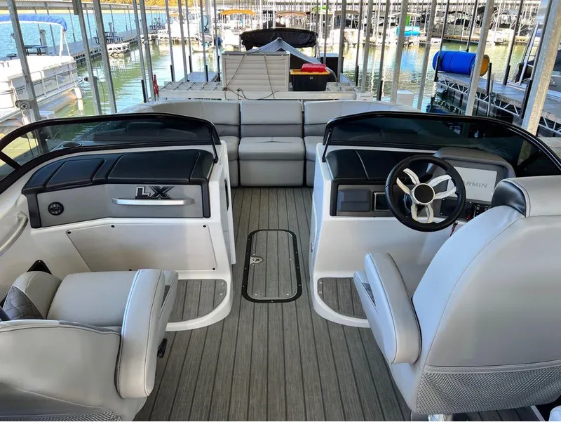 Slide: The Image of 2023 Manitou LX 25 SRW boat interior with split rear windshield, docked at marina. - 43
