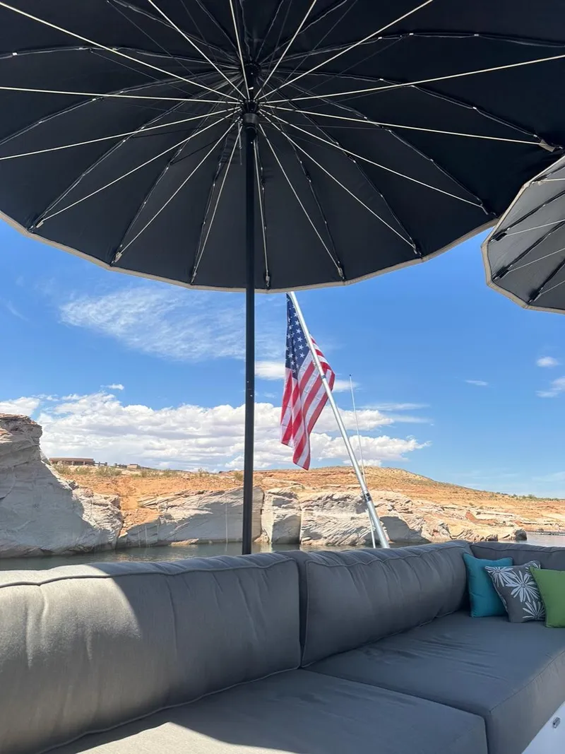 Slide: The Image of Outdoor seating with black umbrellas, American flag, and desert landscape; Adonia Meticulous Share #7, 2023. - 13