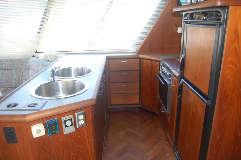 Slide: The Image of 1992 Bayliner 4588 Pilothouse MY kitchen with dual sinks, wooden cabinets, and appliances. - 23