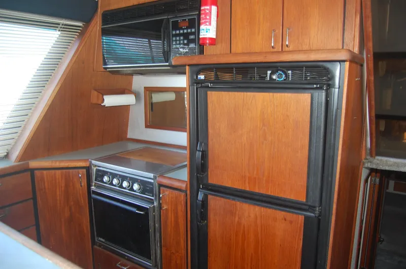 Slide: The Image of 1992 Bayliner 4588 Pilothouse MY kitchen with wood cabinetry, stove, and refrigerator. - 24