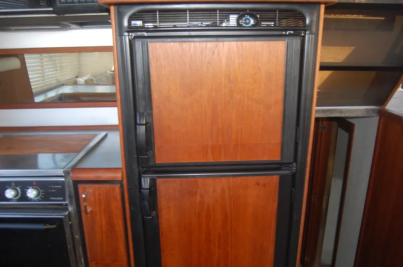 Slide: The Image of 1992 Bayliner 4588 Pilothouse MY galley with wood-paneled refrigerator and stove. - 26