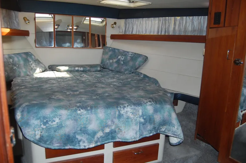 Slide: The Image of 1992 Bayliner 4588 Pilothouse MY cabin with bed, mirrors, and blue bedding. - 30