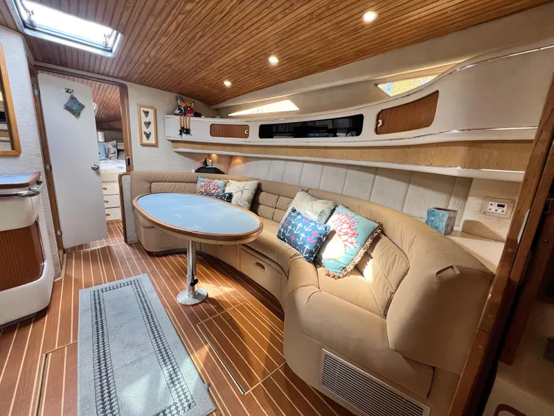 Slide: The Image of 1993 Sea Ray 440 Sundancer interior with cozy seating and wooden accents. - 18